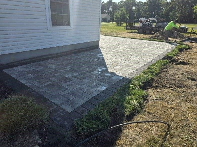 A man is working on a patio in front of a house.