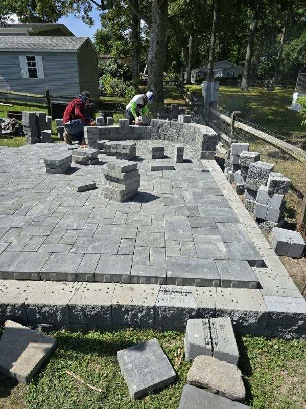 A group of men are working on a patio in a yard.