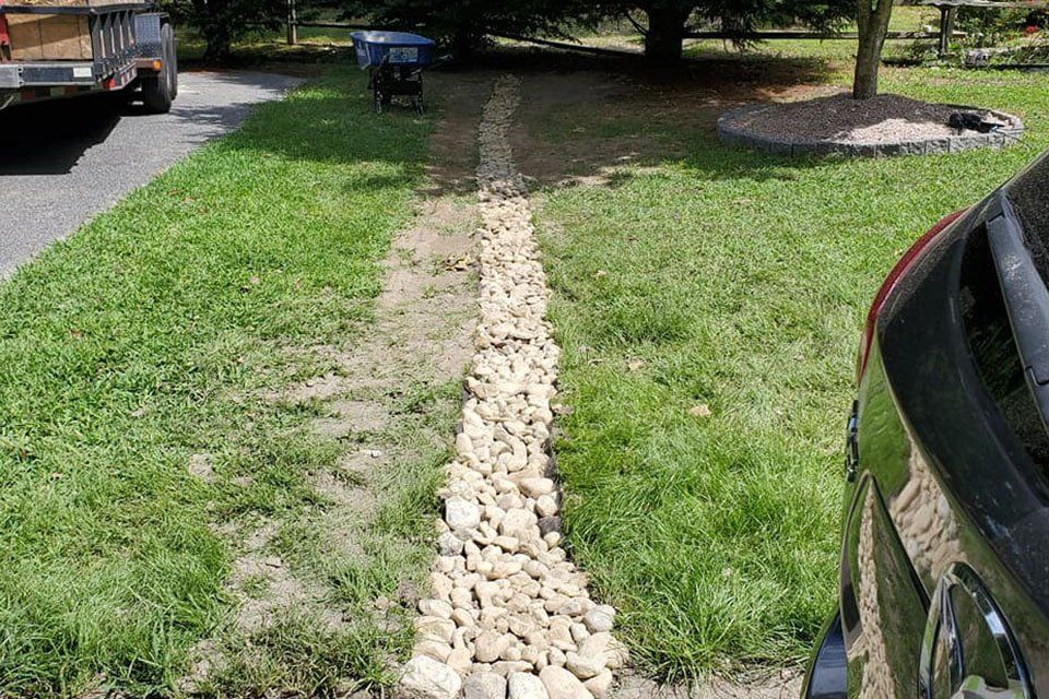 A car is parked on the side of the road next to a rocky path.