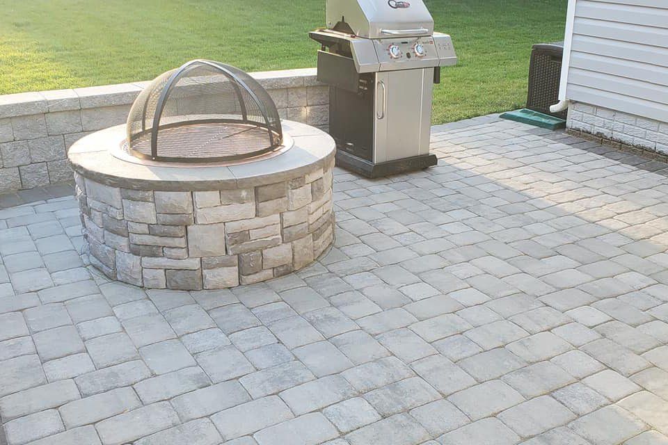 A fire pit is sitting on a patio next to a grill.