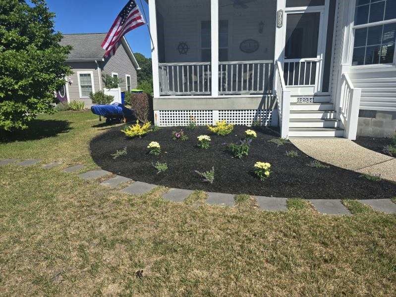 A house with a screened in porch and a garden in front of it.