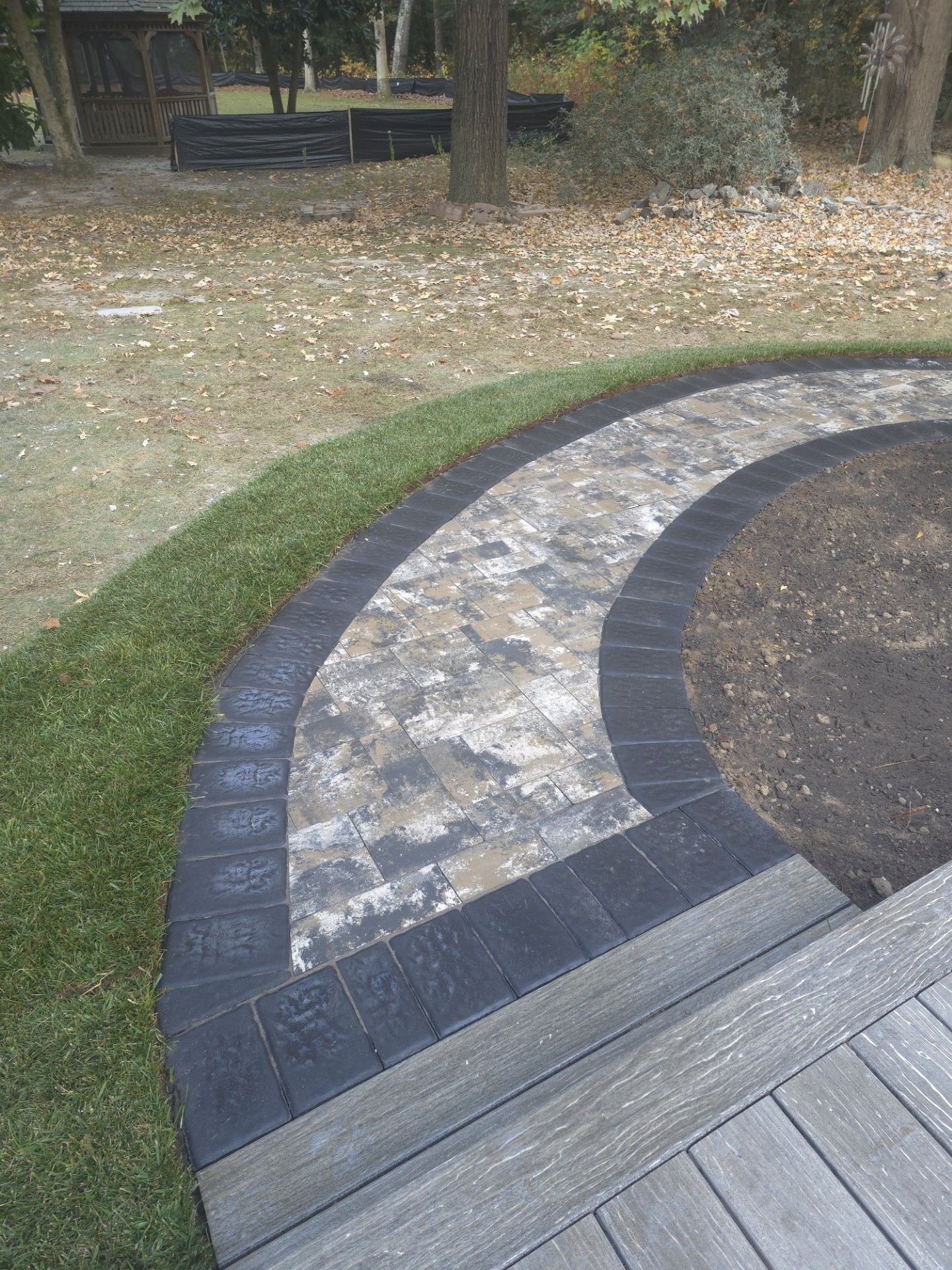 A circular walkway leading to a deck in a backyard.
