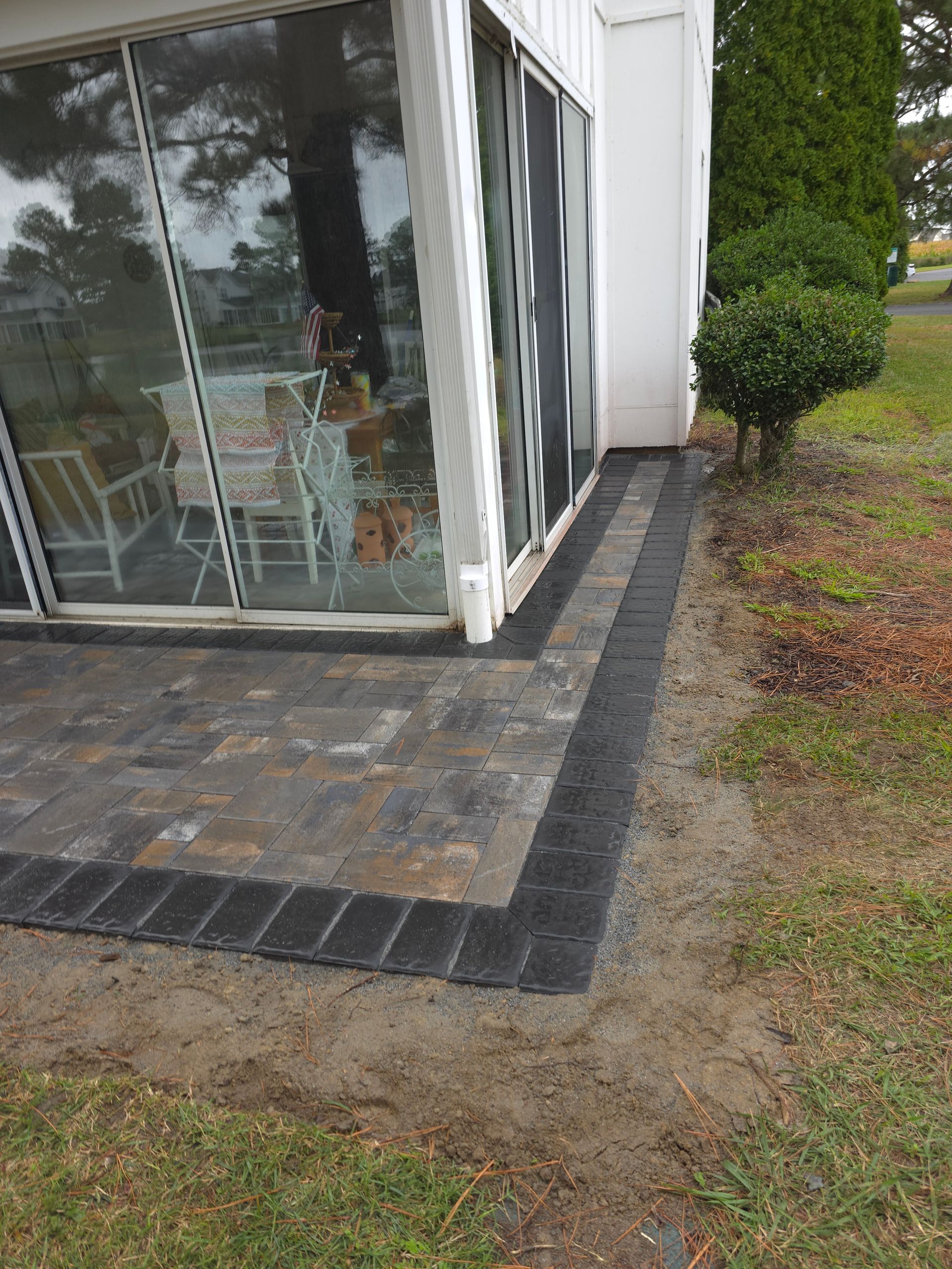 There is a patio in front of a house with a sliding glass door.