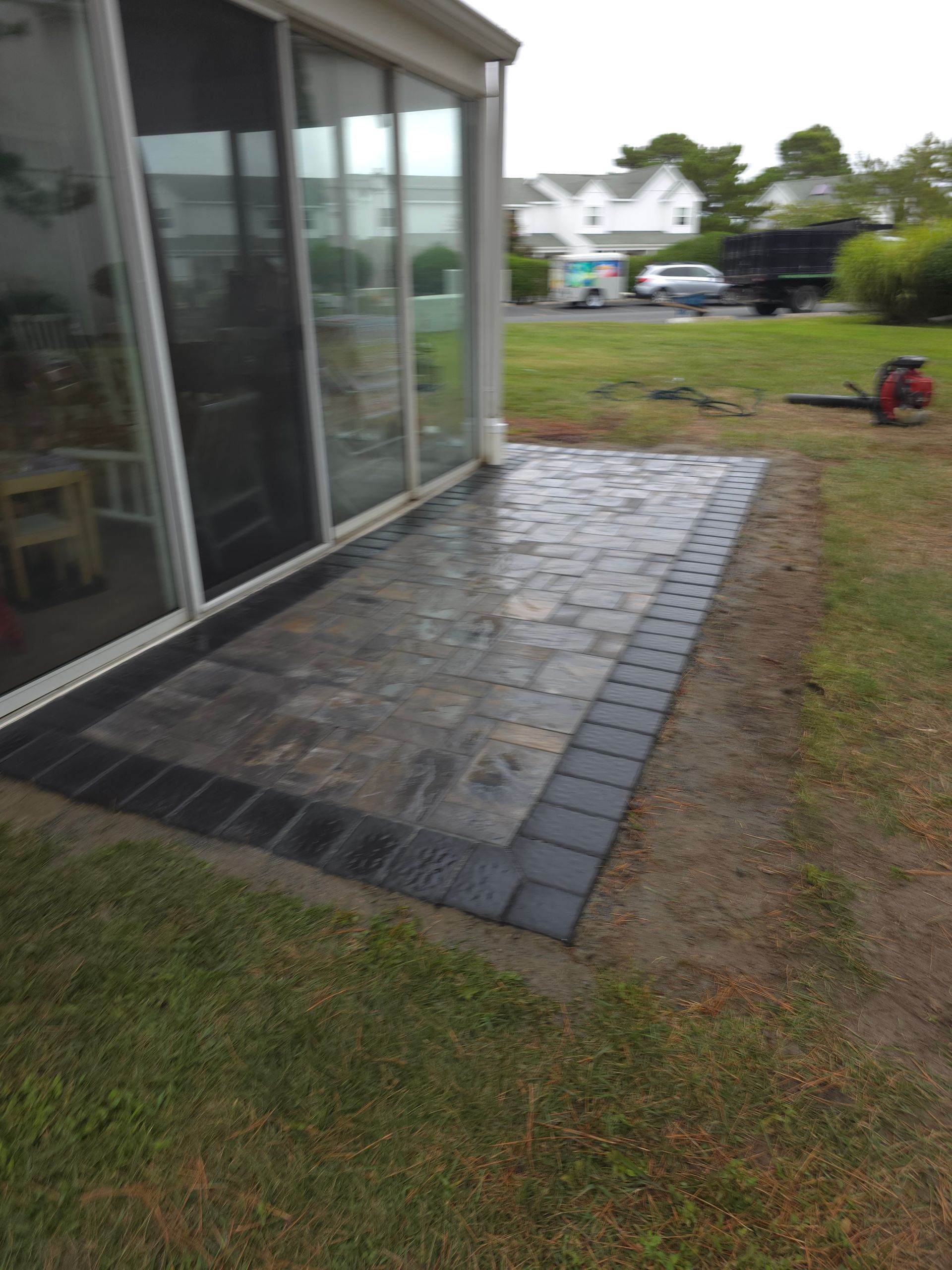 A patio with a sliding glass door is being built in front of a house.