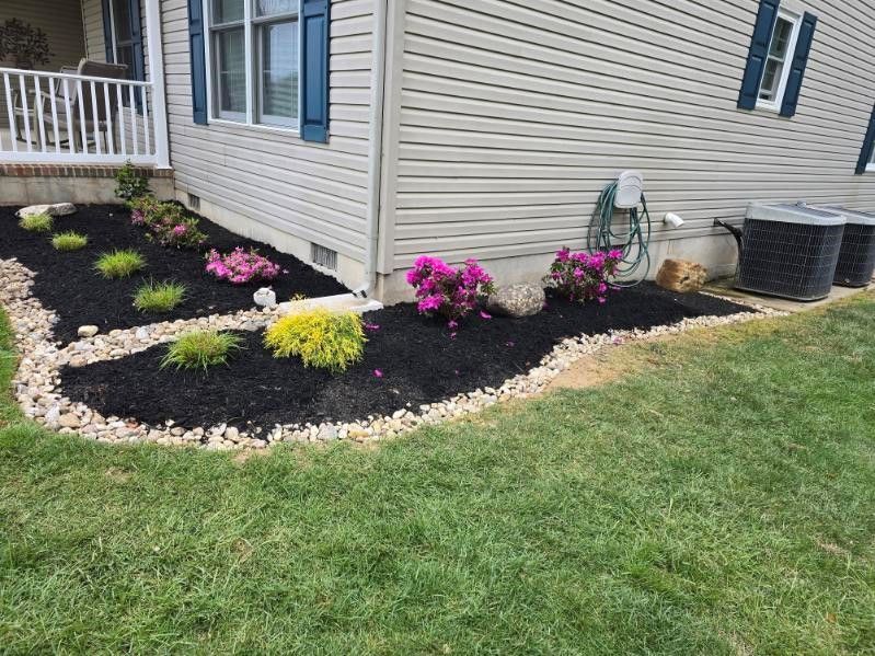 A lawn with flowers and mulch in front of a house.
