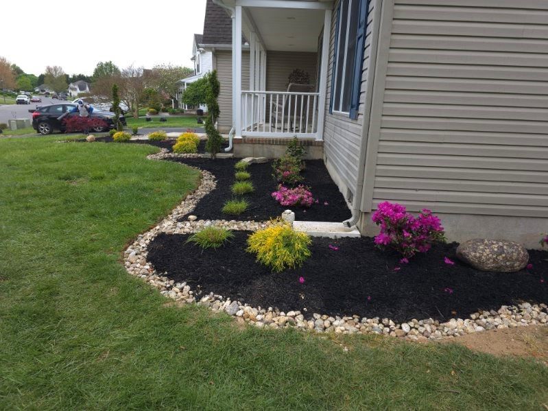 A house with a lush green lawn and flowers in front of it.
