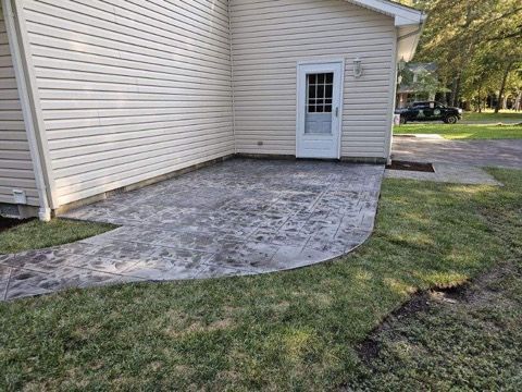 A patio with a walkway leading to a garage door next to a house.