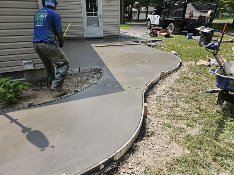 A man is working on a concrete walkway in front of a house.
