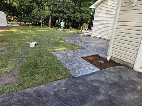 A driveway leading to a house with a patio in front of it.