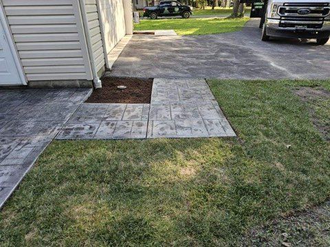 A truck is parked in a driveway next to a house.