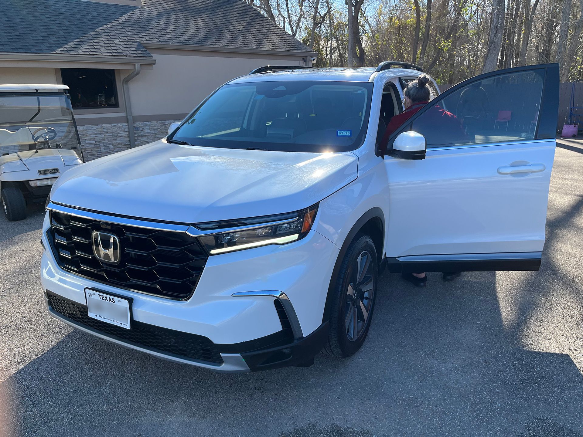 A white Honda Pilot is parked in an auto detailing shop with its doors open