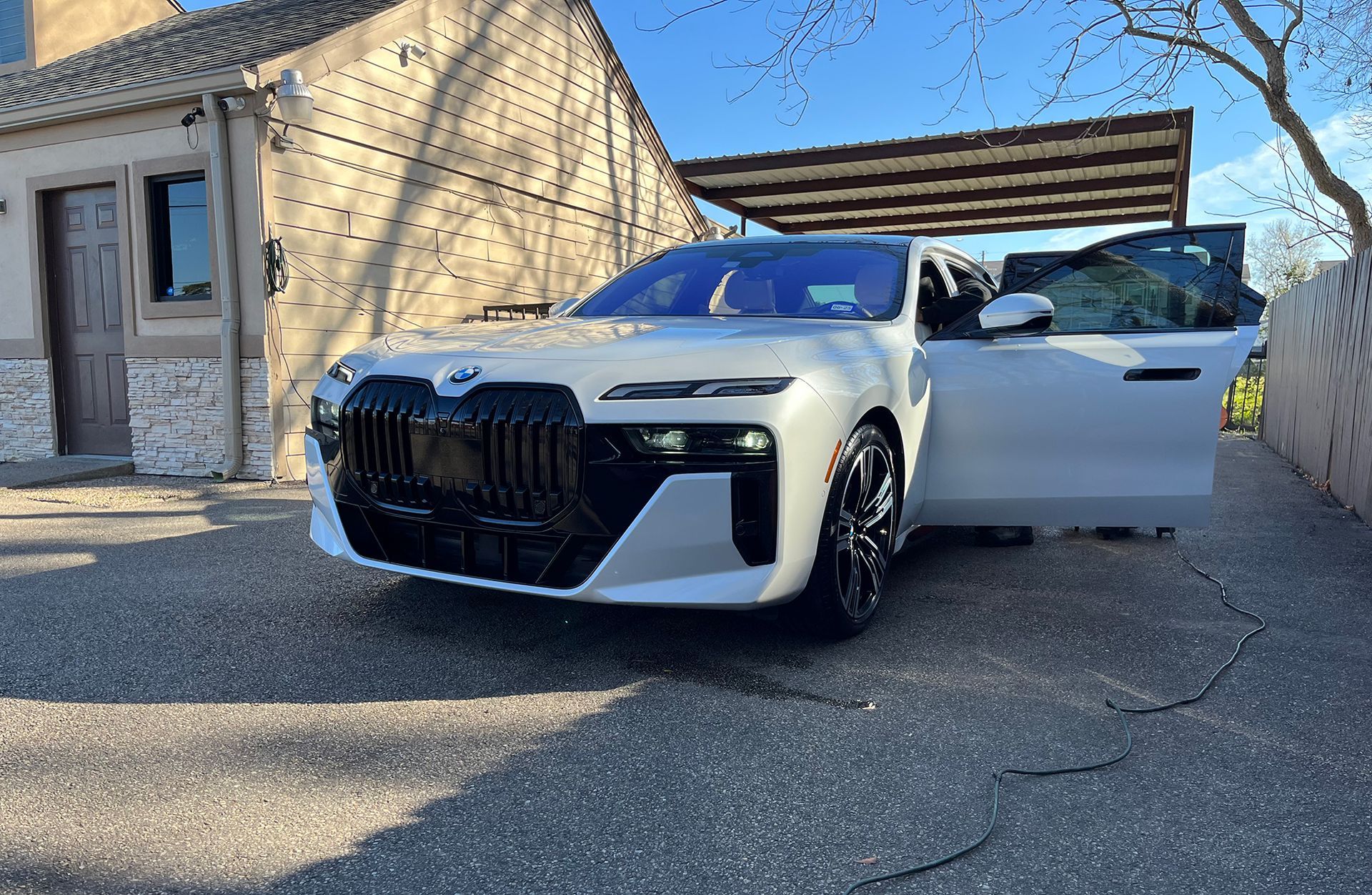A white car is parked in an auto detailing shop with its doors open