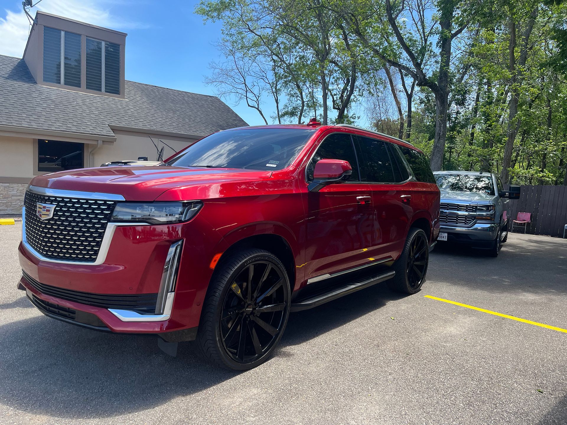 A red Cadillac Escalade is parked in an auto detailing shop