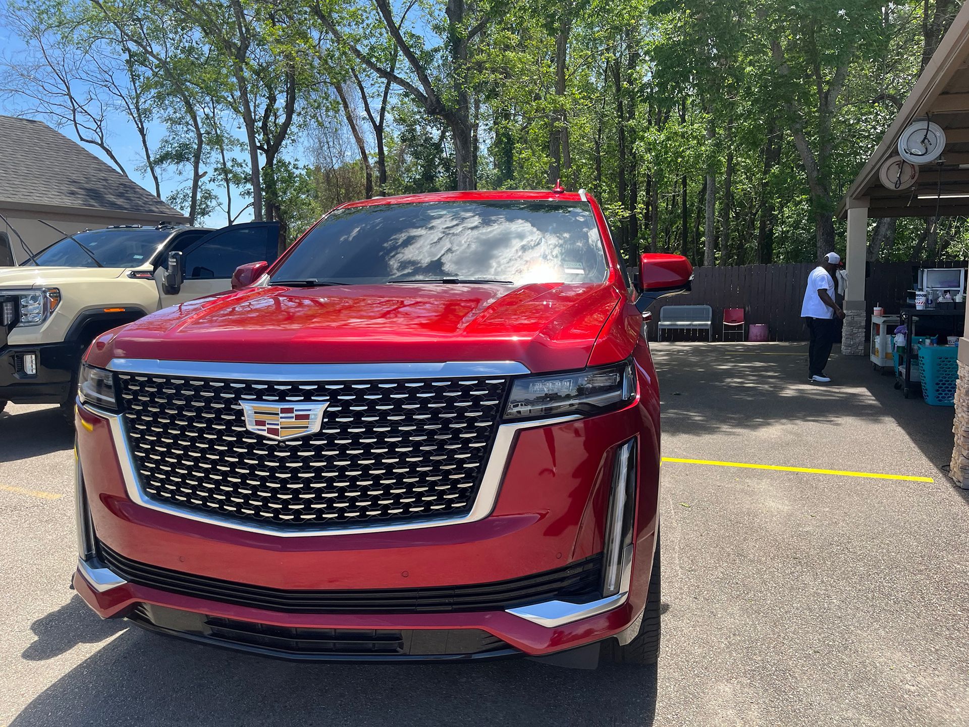 A red Cadillac Escalade is parked in an auto detailing shop