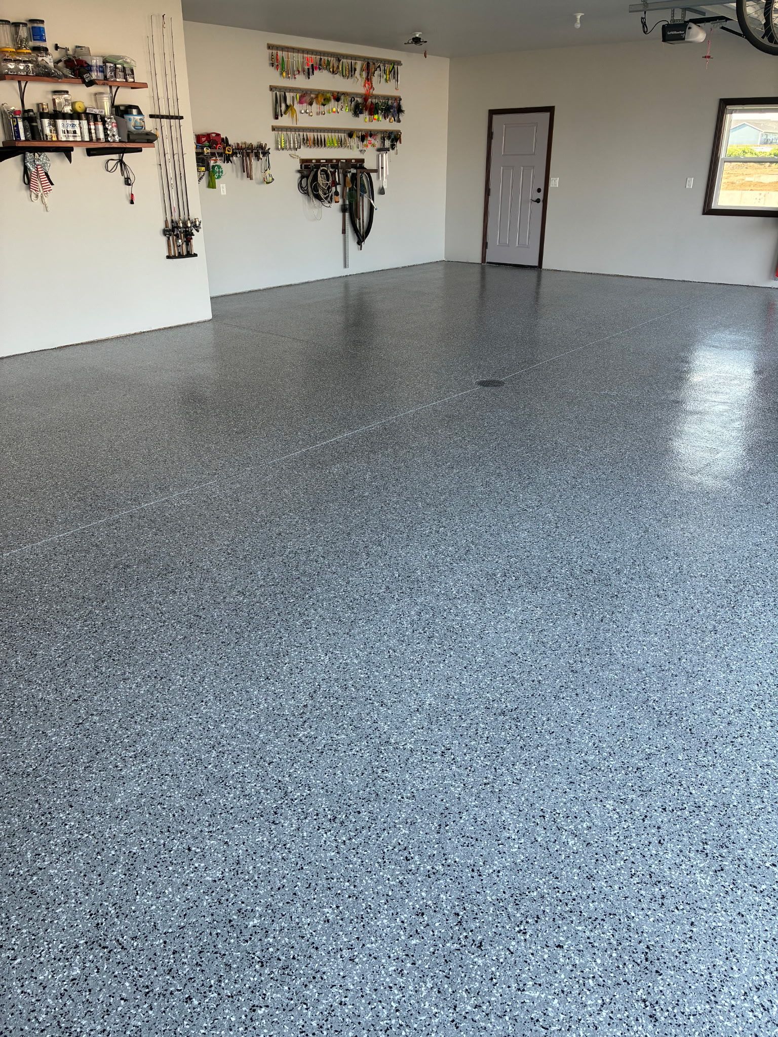 A garage with a speckled gray epoxy floor and organized wall shelving.