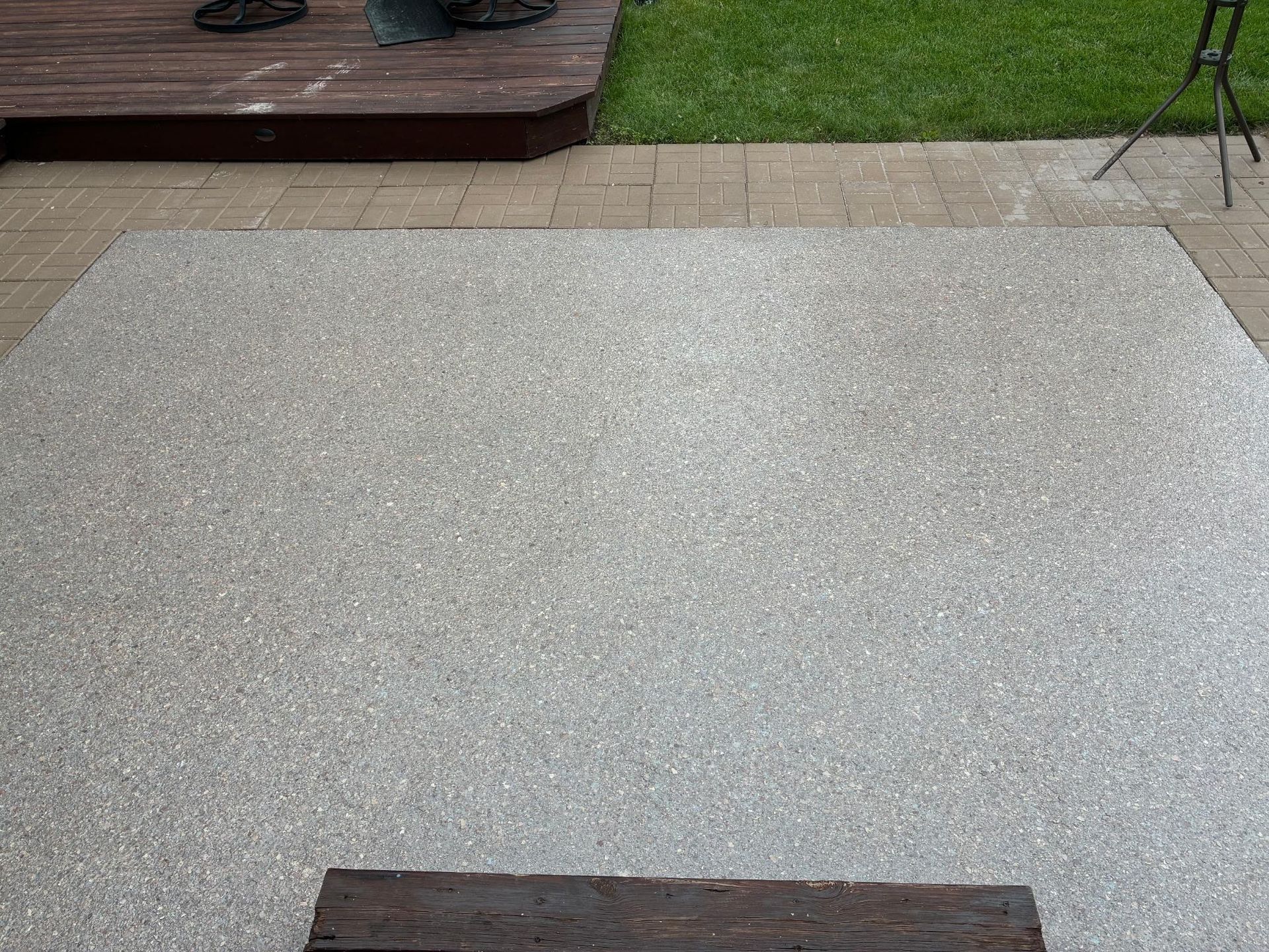 Gray concrete patio with a wooden step and green grass visible.