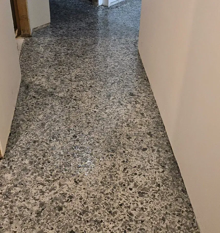 Hallway with polished, speckled gray concrete floor. White walls on either side.