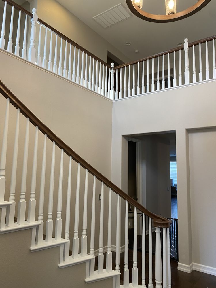 Interior staircase with white railings and beige walls in a two-story foyer