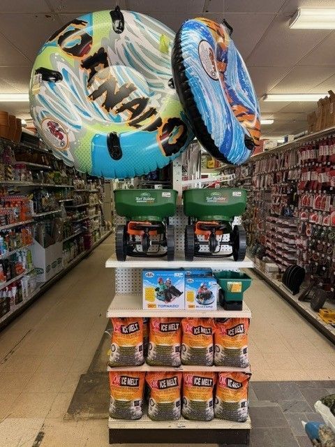 Store display with pool floats, lawn spreaders, and bags of fertilizer on shelves.