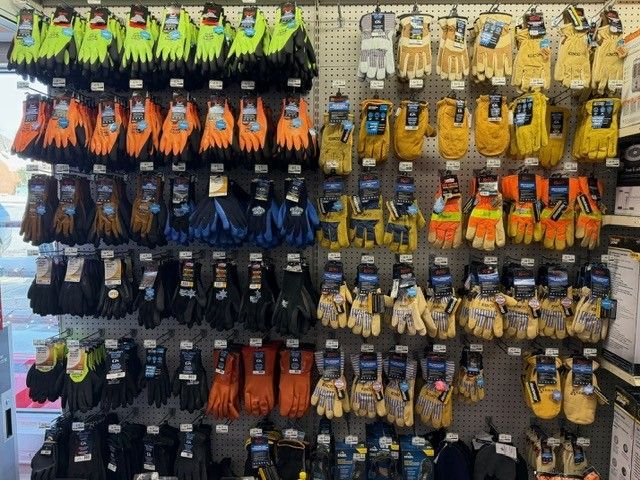 Gloves displayed on a store rack; various colors including green, orange, yellow, and blue.
