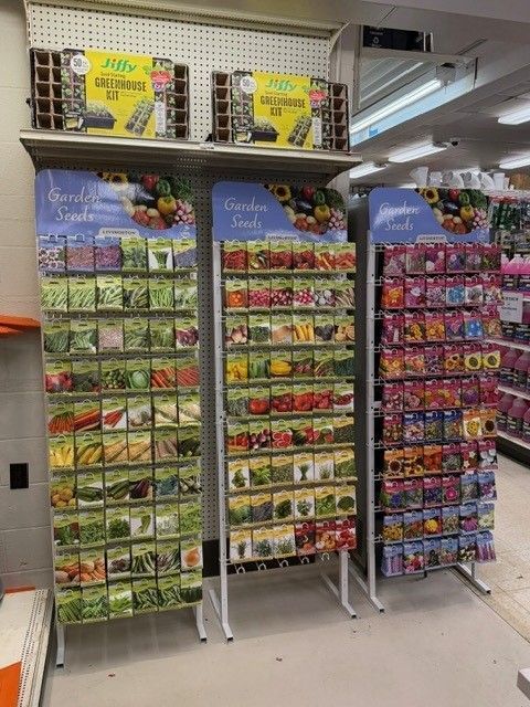 Seed packet display in a store, offering various vegetable and flower seeds.