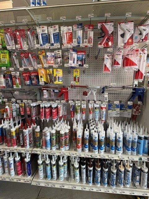 Shelves stocked with caulk tubes and applicators in a hardware store.