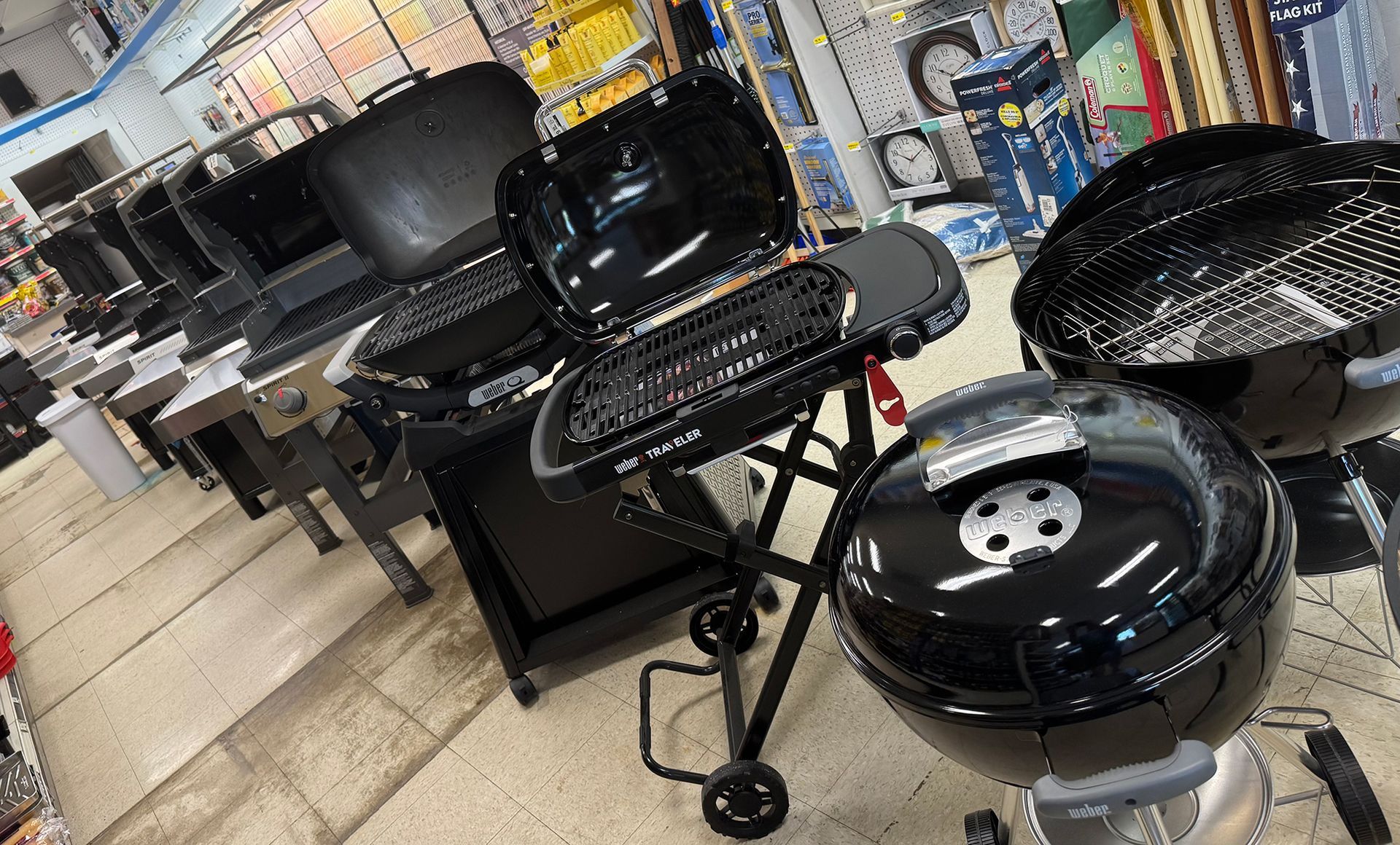 A bunch of grills are sitting on the floor in a store.