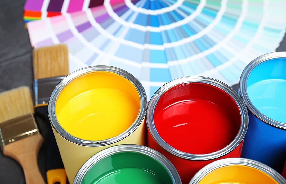 A bunch of cans of paint and brushes on a table.