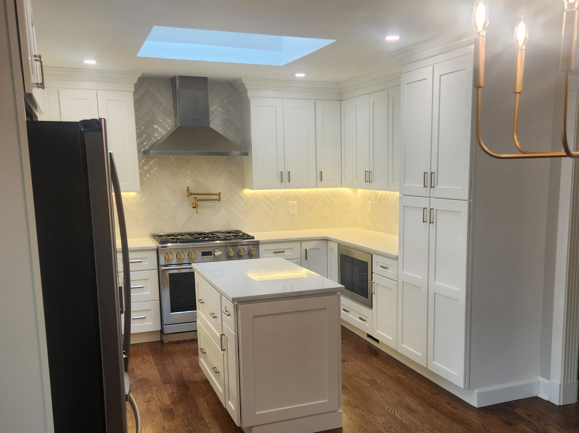 A kitchen with white cabinets, stainless steel appliances, and a large island.