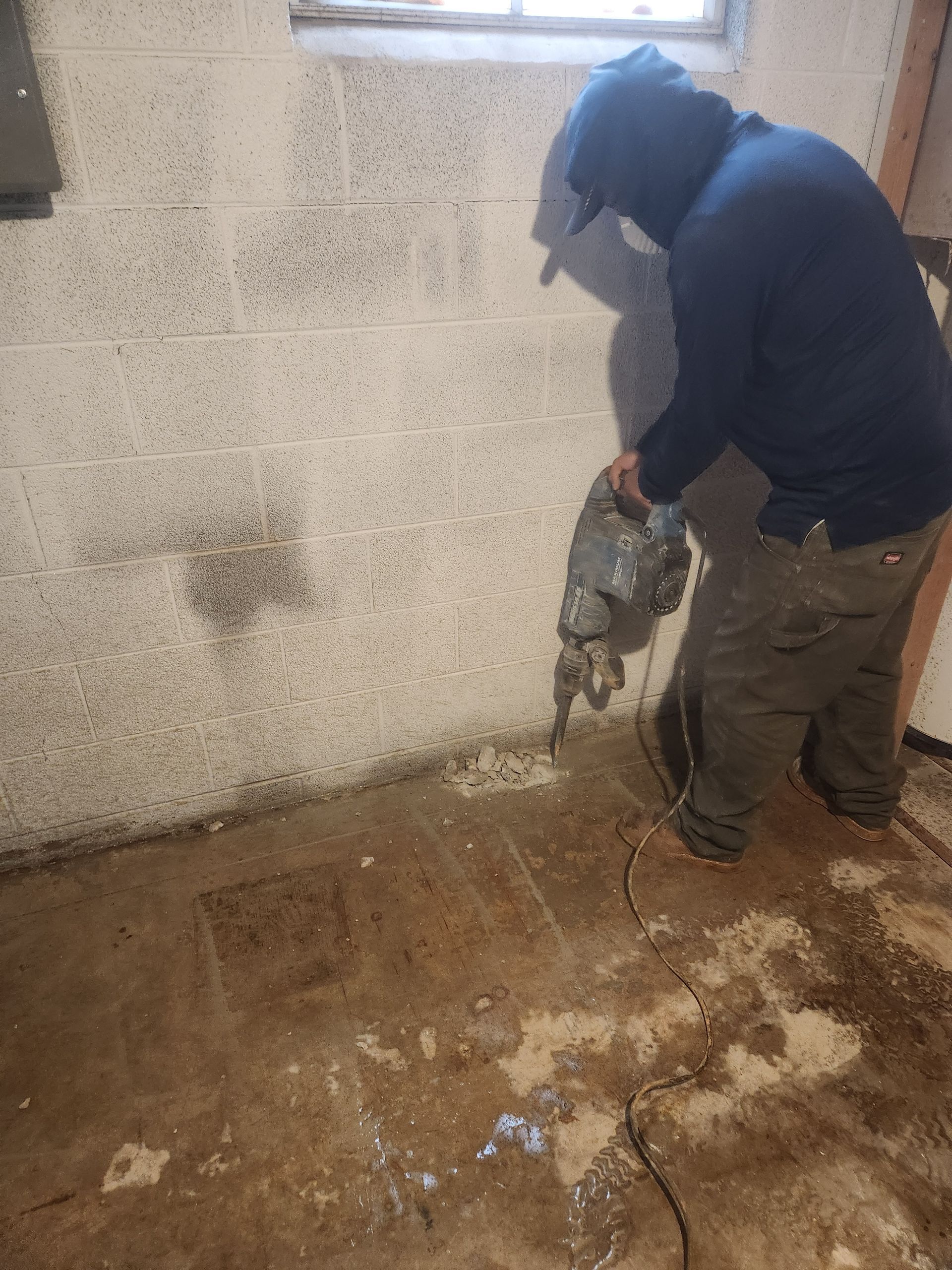 A man is cutting a hole in a wall with a saw.