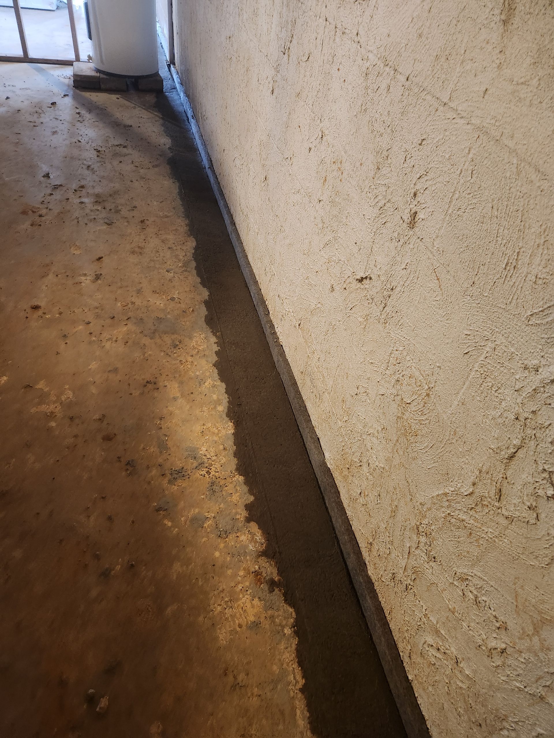 A concrete floor next to a wall in a basement.