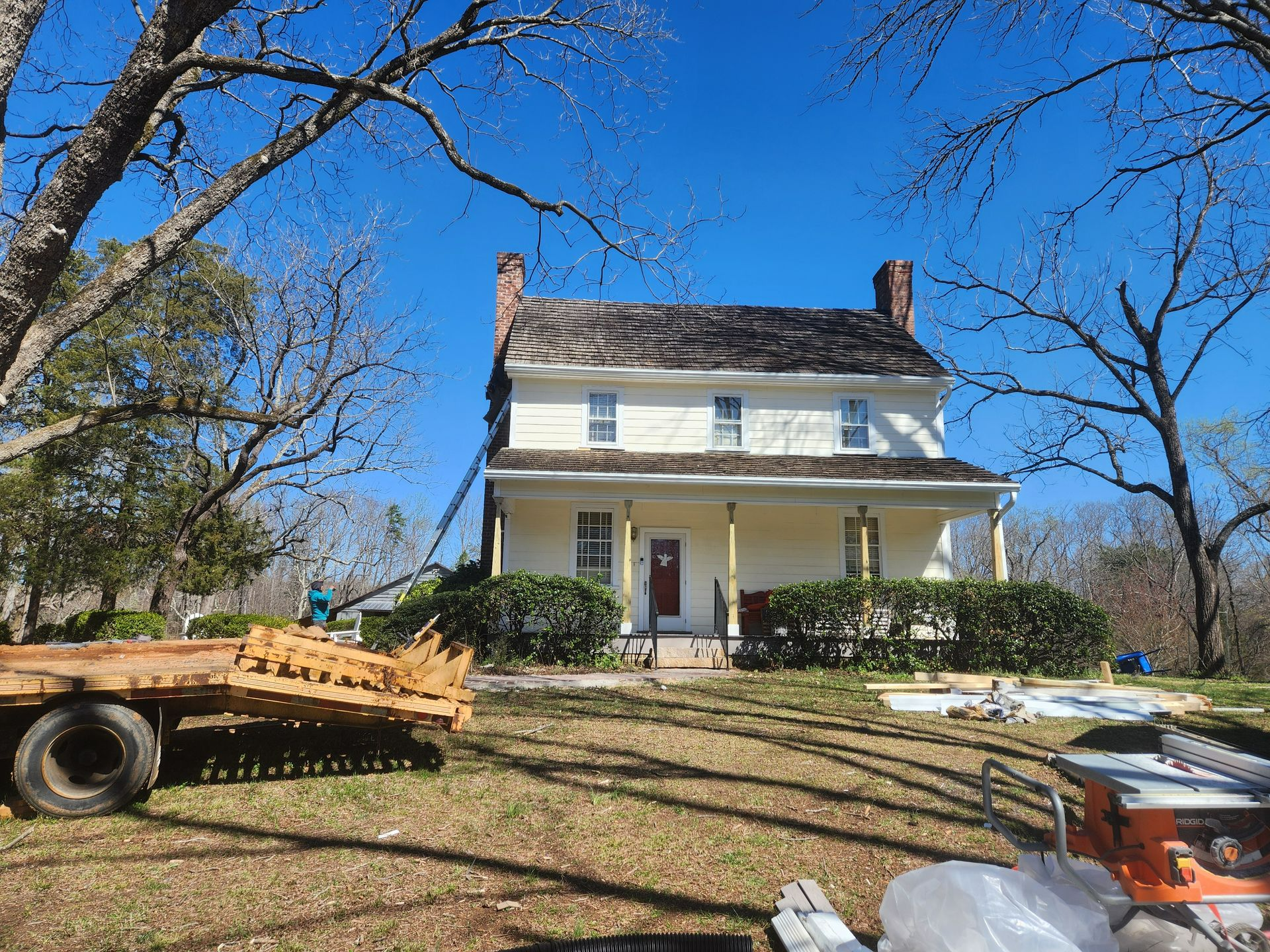 A large white house with a wooden trailer parked in front of it.