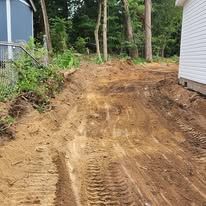 A dirt road leading to a house in the woods.