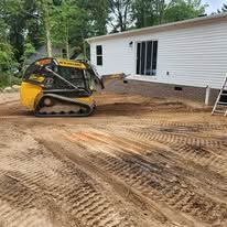 A yellow bulldozer is moving dirt in front of a mobile home.