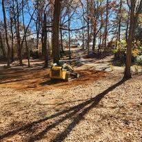 A bulldozer is moving dirt in a forest.