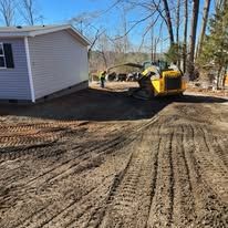 A yellow bulldozer is moving dirt in front of a house.