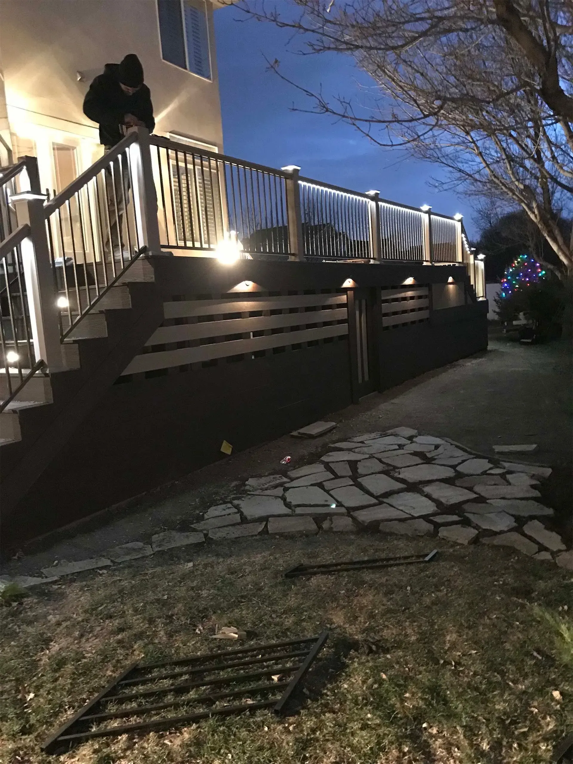 Lit deck at dusk with stone path leading down. Person on deck.