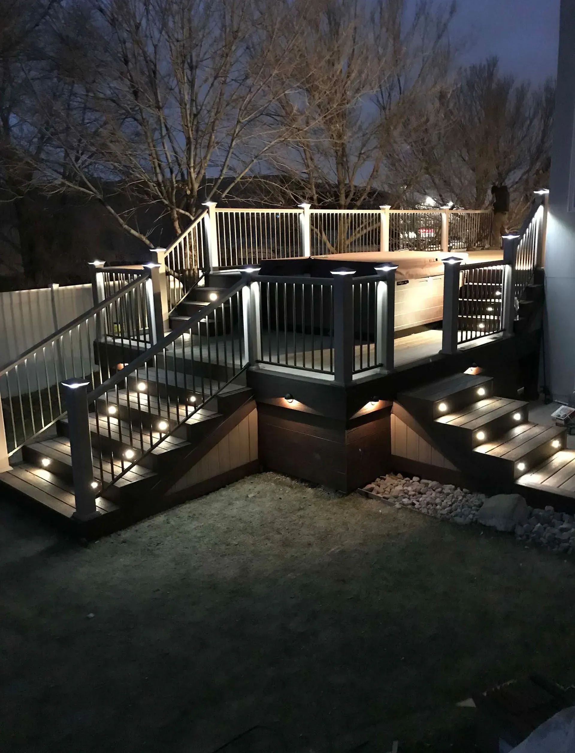 Lit wooden deck with stair lights at dusk.