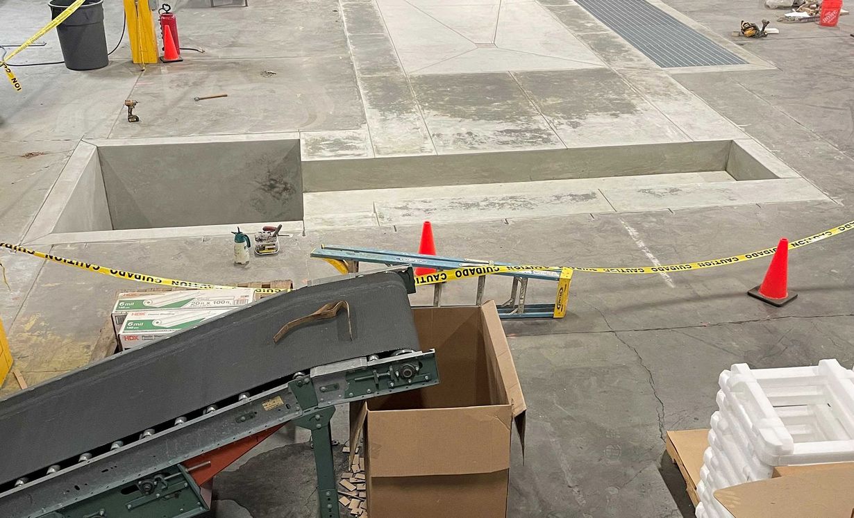 Caution-taped construction area with concrete steps, orange cones, and cardboard boxes on a sidewalk