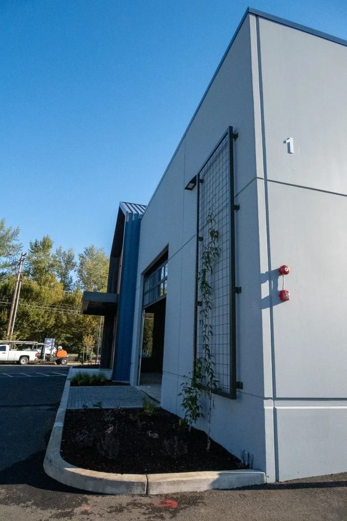 Modern gray building exterior with barred windows and a small entryway under a blue sky