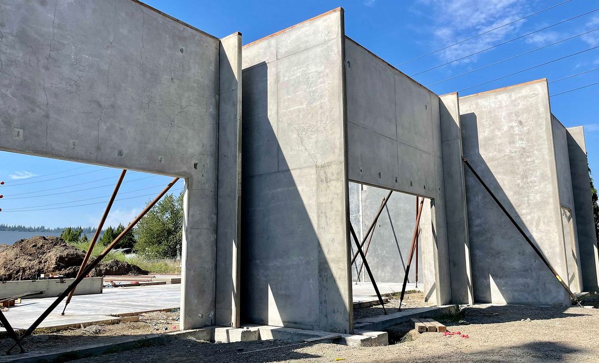 Concrete wall panels under construction on a sunny building site, with braces and open sky.