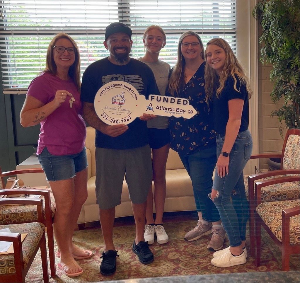 Five people stand indoors holding a large decorative key that says 