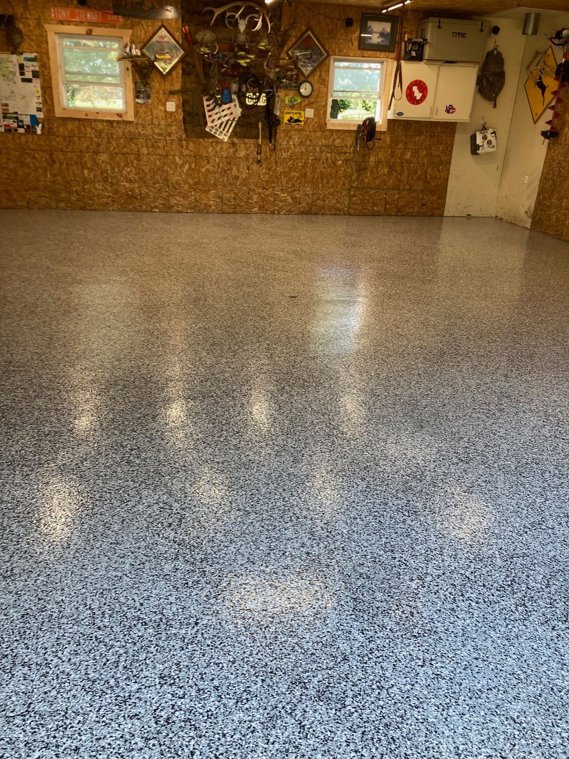 Garage with epoxy floor; tan walls and various decorations, including windows and tools.