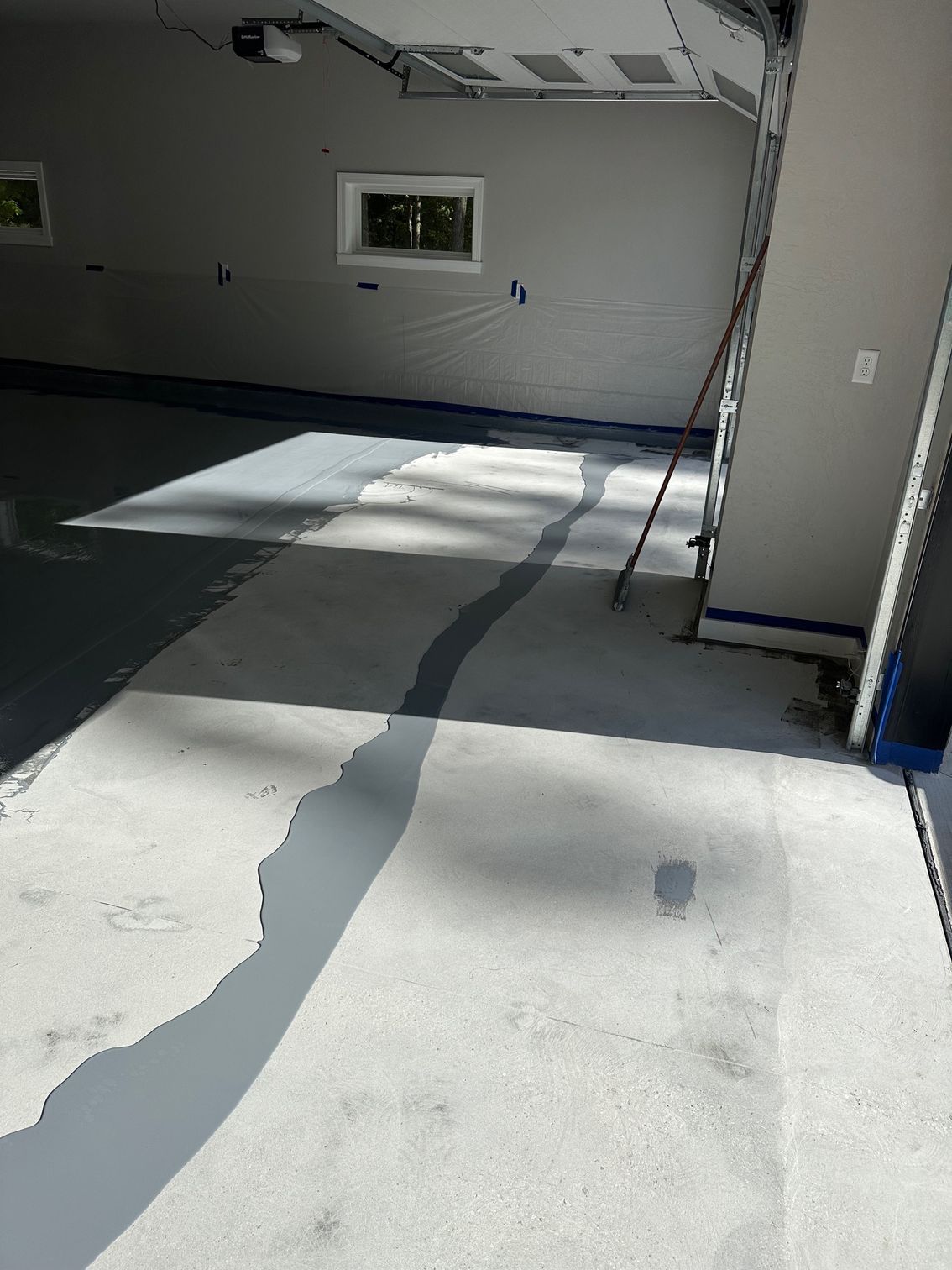 Garage with light gray epoxy floor and walls, partially painted with dark gray epoxy.