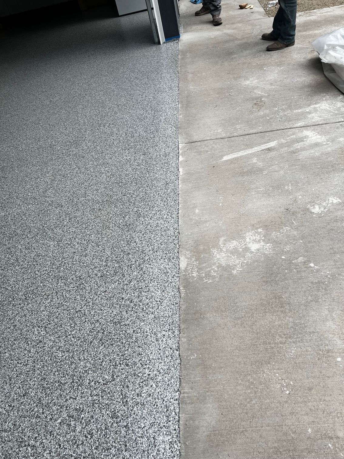 Gray speckled epoxy flooring next to plain concrete surface.