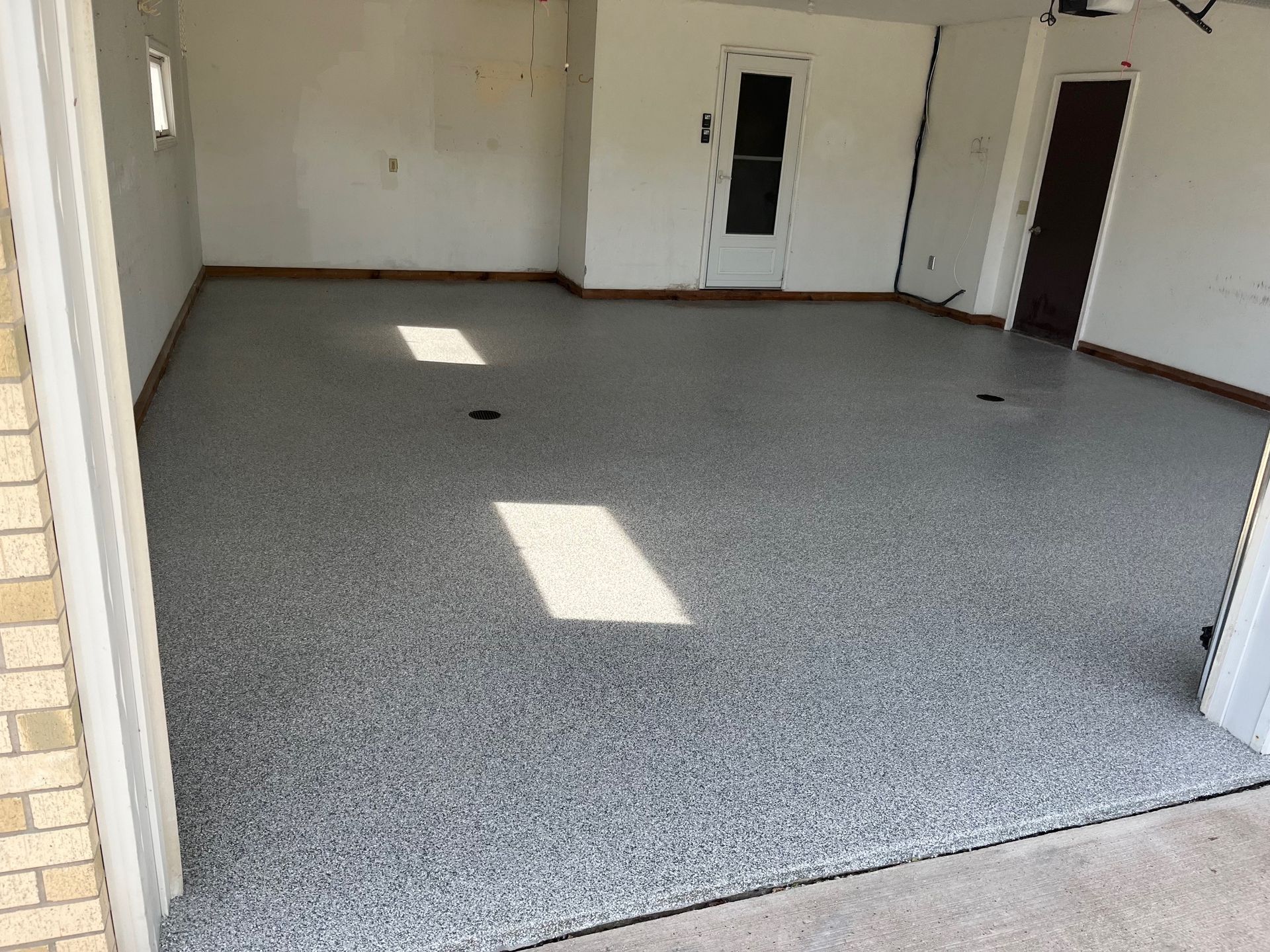 Garage interior with gray speckled epoxy floor and white walls.