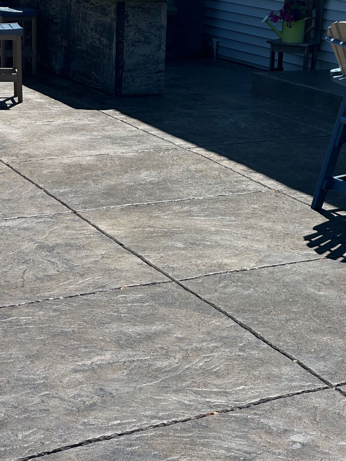 Concrete patio with dark lines, in sunlight.