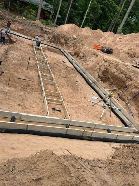 Construction site with workers, wooden forms, and a ladder on a hillside.