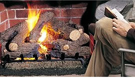 A man sitting in front of a  fireplace while reading a book