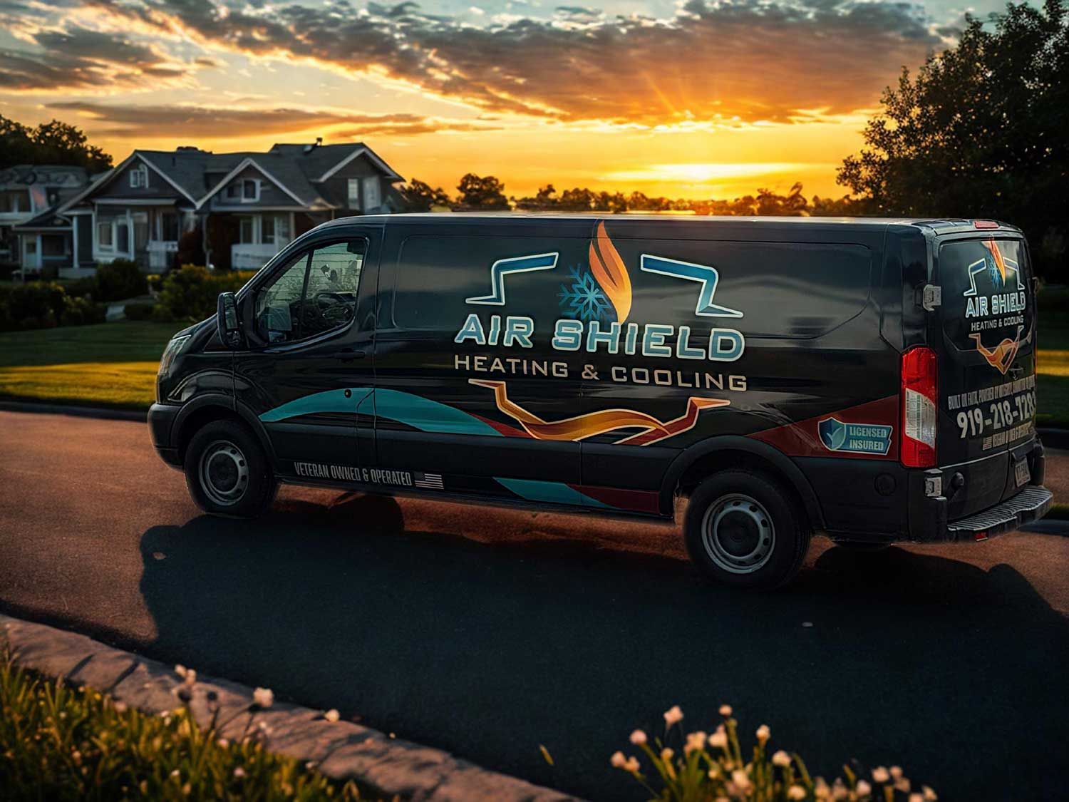 Black van with "Air Shield Heating & Cooling" logo parked on a street at sunset. Houses in the background.